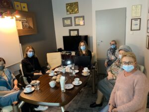 Elderly people sitting around a meeting table with face masks on.